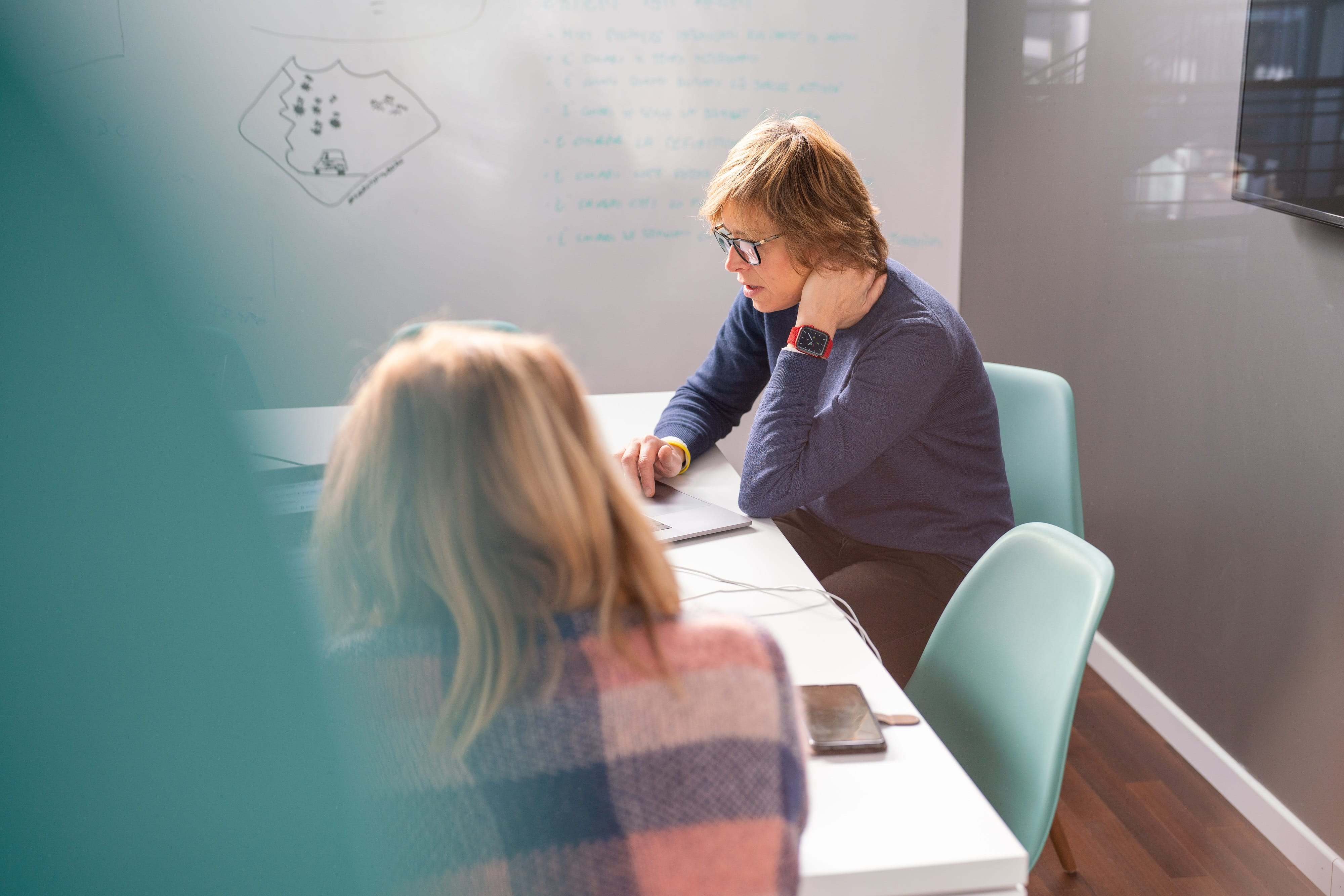 Due donne sedute a un tavolo in una sala conferenze.