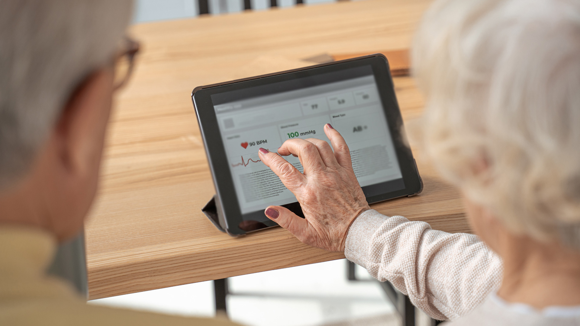 Picture of two senior individuals interacting with a digital device.