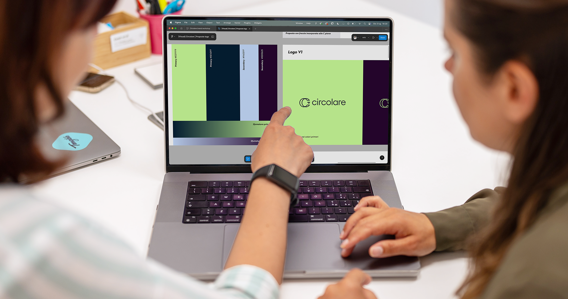 Due persone collaborano su una schermata su laptop che mostra il logo e la palette cromatica di Circolare all’interno di un file di design su Figma.